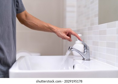 The faucet in the bathroom with running water. Man keeps turn off the water to save water energy and protect the environment. save water concept - Shutterstock ID 2029195178