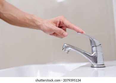 The faucet in the bathroom with running water. Man turning off the water to save water energy and protect the environment. world environment day - Shutterstock ID 2079395134