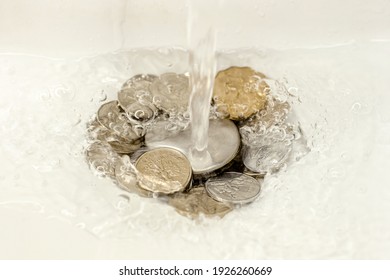 Faucet With Water And Coins. Money Down The Drain. Concept: Expensive Utilities. Water Leakage, Misuse Of Water. High Cost Of Water.