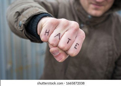 Faust with the word hate in English as a symbol of hate and brutality - Shutterstock ID 1665872038