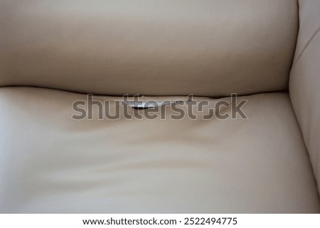 Faux leather sofa with torn seams. Creative beige background, leather texture.