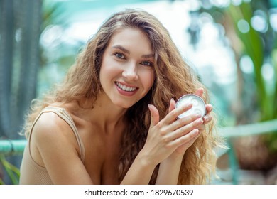 Favourite Product. Cute Woman Sitting And Holding A Jar Of Cream In Her Hands