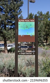 Fawnskin, California - USA - May 22, 2022: The Alpine Pedal Path Sign With Map With Route. Serrano Campground, Meadow Edge (Lake Access) And Cougar Crest Trail Sign At The Discovery Center.