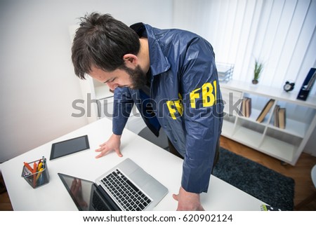 FBI agent in his office working on a case and using laptop