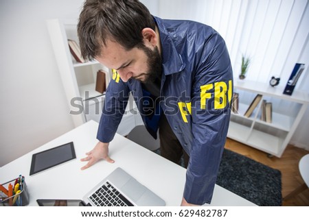FBI agent in his office working on a case and using laptop alone