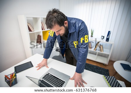 FBI agent in his office working on a case and using laptop