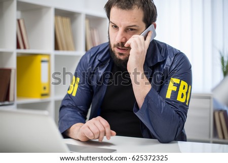 FBI agent talking on mobile phone in office