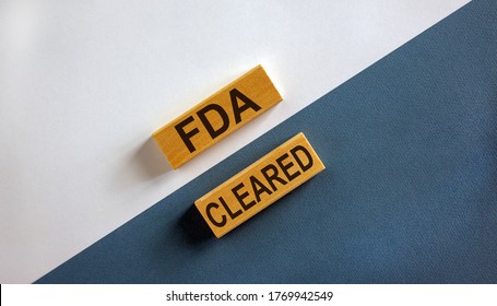 'FDA cleared' words on wooden blocks. Business concept. Beautiful white and blue background.