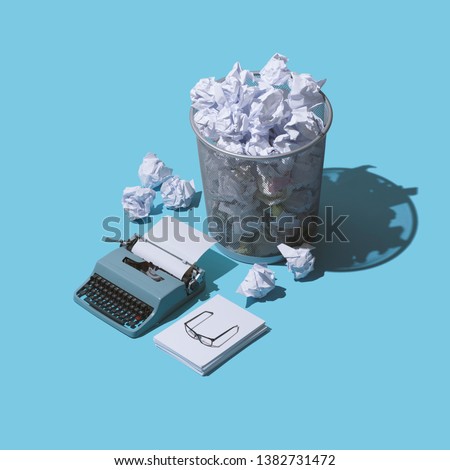Fear or the blank page and lack of creativity: vintage typewriter with blank sheet and lots of crumpled paper balls in a trash can