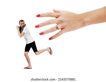 Fear Of Commitment. A Young Man Trying To Run Away From A Giant Hand Wearing A Wedding Ring.