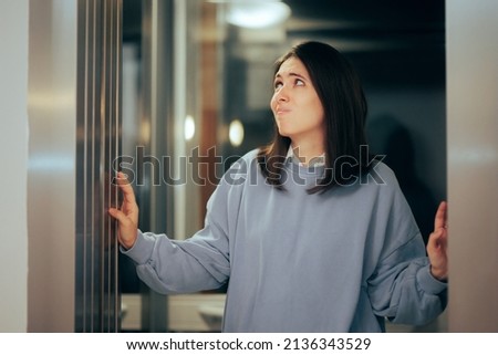 
Fearful Claustrophobic Woman Entering an Elevator with Caution. Stressed anxious office worker afraid of being stuck in the lift 
