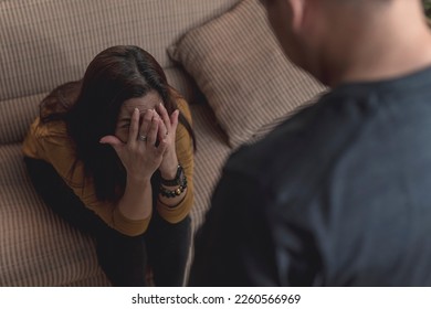 A fearful wife looks up to her abusive husband, afraid of being hit. Example of a victim in domestic abuse and physical violence in couples.