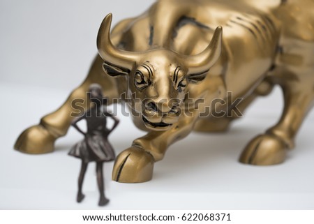 Fearless girl stands in front of charging bull.  Bull in focus.