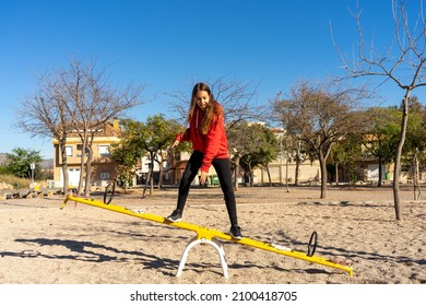 Fearless Preteen Girl Balancing Climb On A Toy Seesaw In A Park, Mentally Preparing Herself To Make Good Decisions In Life.