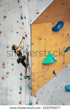Fearless and tenacious. Portrait of happy teen girl climbing the rock wall. Sport weekend action in adventure park. Active lifestyle concept