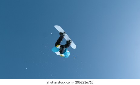 Fearless young male snowboarder does a breathtaking backflip after jumping off a massive kicker. Man snowboarding in the Chinese mountains performs a spectacular flip while riding in a snowboard park.