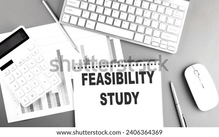 FEASIBILITY STUDY text written on notebook on grey background with chart and keyboard, business concept