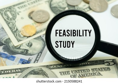 Feasibility Study.Magnifying glass showing the words.Background of banknotes and coins.basic concepts of finance.Business theme.Financial terms. - Shutterstock ID 2150588241