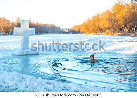 Feast of the Baptism of the Lord. The Orthodox rite of bathing in an ice-hole. Epiphany. A man bathes in ice water on a holiday. Dipping in water near the cross made of ice