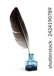 Feather with a glass bottle of ink. Feather in a blue vintage inkwell