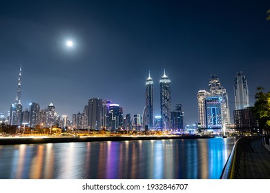 Feb 26th , 2021 Dubai, UAE. Panoramic view of the illuminated  Burj Khalifa with other skyscapers throwing beautiful reflections on water captured from the Dubai canal boardwalk, Dubai, UAE.