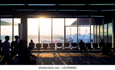 February 15, 2019 - Bangkok, Thailand :: Morning Light Shines In “Don Mueang International Airport” With Sillhouette Of Passengers And The Airplane Of “Thai Lion Air” Outside