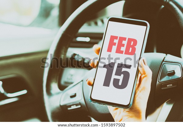 february
15th. Day 15 of month,Calendar date. Month and day placed on a
smartphone screen in womans hand in car interior. artistic
coloring.  winter month, day of the year
concept