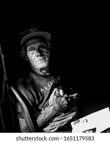 February 2, 2020 Sabana Larga, Dominican Republic. Dramatic Black And White Image Of Old Man Reading Magazine On His Porch In Sabana Larga, 