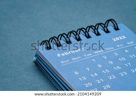 February 2022 - spiral desktop calendar against textured paper, time and business concept