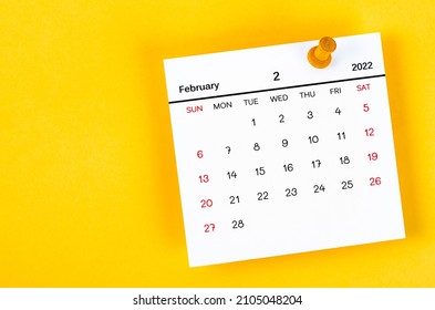 The February 2022 and wooden push pin on yellow background.