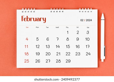 February 2024 Monthly desk calendar for 2024 year and pen on red background.