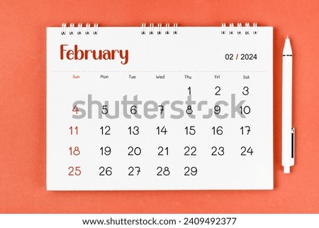 February 2024 Monthly desk calendar for 2024 year and pen on red background.