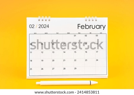 February 2024, Monthly desk calendar for 2024 year and pen on yellow color background.