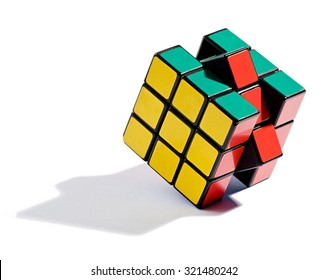 February 24, 2014 - Milan, Lombardy, Italy : Solving The Rubiks Cube Puzzle With The Final Colored Squares Being Moved Into Place, Standing On Edge On A White Background Casting A Shadow