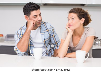 Fed Up Couple Having Coffee Looking At Each Other At Home In Kitchen