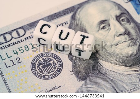FED, Federal Reserve with interest rate cut concept, small cube block with alphabet building the word CUT next to Federal Reserve emblem on US Dollar banknote.