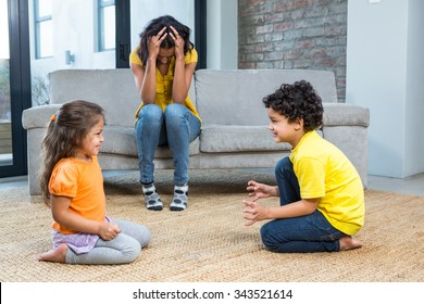 Fed Up Mother Listening To Her Young Children Fight At Home In The Living Room