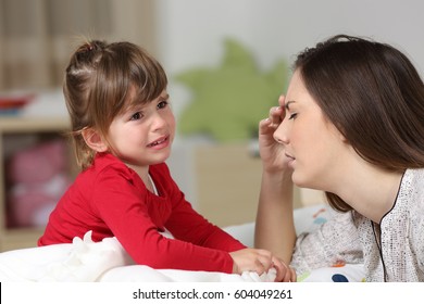 Fed Up Woman Listening To Her Two Years Old Daughter Crying Sitting On The Bed In A House Interior