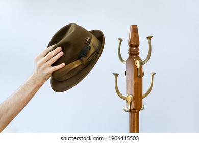 Fedora Hat Hanging On A Wooden Old Fashioned Antique Hat Rack Isolated On White Background. Rustic Traditional Vintage Style Head Wear On Coat Hanger. Hand Holding A Fedora