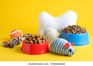 Feeding Bowls And Toys For Pet On Yellow Background