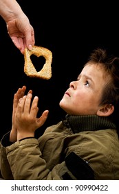 Feeding The Poor Concept With Dirty Kid Receiving Slice Of Bread - On Black