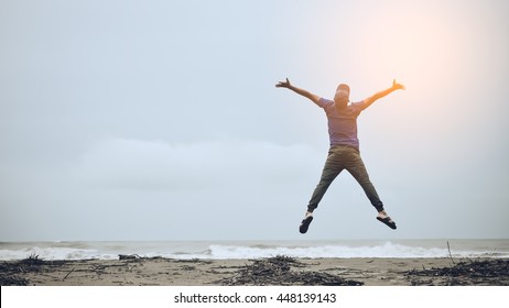 Feel good and freedom concept. Copy space of happy man jumping on beach. Vintage tone color style. - Shutterstock ID 448139143