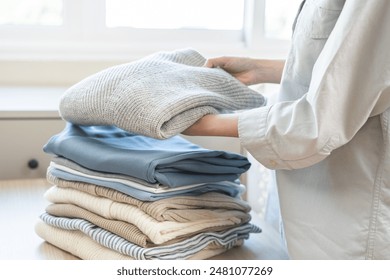 Feel softness, chore of asian young woman, girl housewife hand folding clean clothes after washing, laundry and dry, holding pile, stack clothing from table working at home. Laundry maid in household. - Powered by Shutterstock