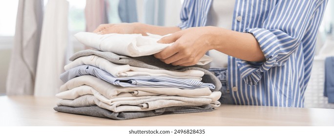 Feel softness, chore of asian young woman, girl hand holding pile clothing from table, stack folding clean clothes after washing, laundry and dry. Household working at home. Laundry of maid concept. - Powered by Shutterstock