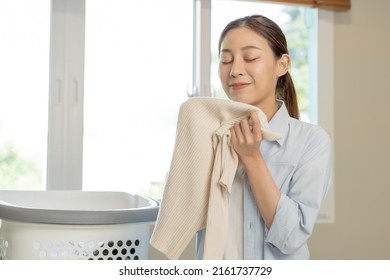 Feel Softness, Smiling Asian Young Woman, Girl Touching Fluffy Towel Cotton, Smelling Fresh Clean Clothes On Table After Washing, Laundry, Dry. Household Working At Home. Laundry And Maid.