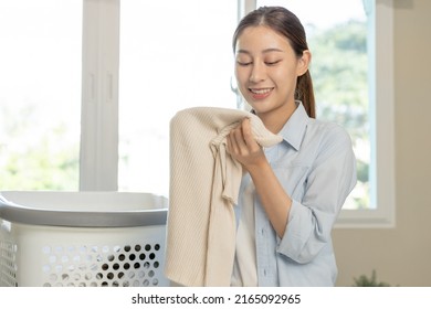 Feel Softness, Smiling Asian Young Woman, Girl Touching Fluffy Towel Cotton, Smelling Fresh Clean Clothes On Table After Washing, Laundry, Dry. Household Working At Home. Laundry And Maid.