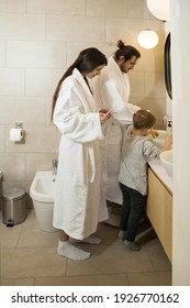 Feeling Comfortable. Nice Boy Playing With His Toy Ducks At The Sink While Brushing His Teeth In The Bathroom With His Family. Stock Photo