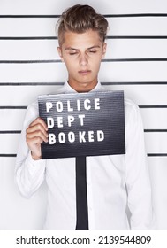 Feeling The Consequences. Mug Shot Of A Young Man In A Shirt And Tie Holding Up A Police Department Sign.