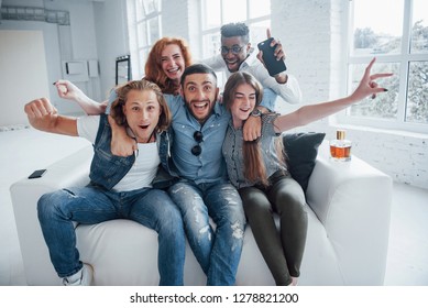 Feeling free. Funny young friends having fun sitting on the sofa in the white interior. - Powered by Shutterstock