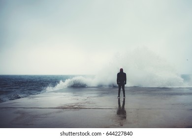 Feeling of freedom, back view of adult man standing on pier facing to the sea with big waves beats against the shore on a cloudy autumn day, alone depress person,the power of nature, storm on seashore - Powered by Shutterstock